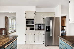 Kitchen with wood counters, light wood-style flooring, blue cabinetry, stainless steel appliances, and a baseboard radiator