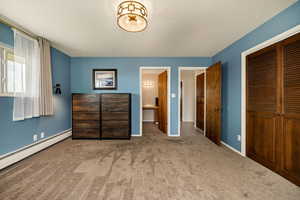 Bedroom featuring a baseboard heating unit, carpet, a closet, and baseboards
