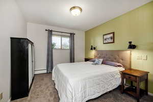 Carpeted bedroom with a baseboard heating unit