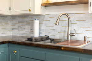 Kitchen with a sink, backsplash, white cabinets, and dark countertops