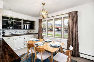 Dining room featuring light wood finished floors, a notable chandelier, and a baseboard heating unit