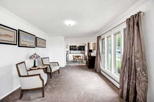 Living area featuring baseboard heating, carpet flooring, baseboards, and ornamental molding