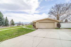 Single story home featuring an attached garage, fence, brick siding, a front lawn, and driveway
