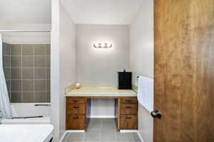 Full bath with tile patterned floors, shower / bath combo with shower curtain, and baseboards