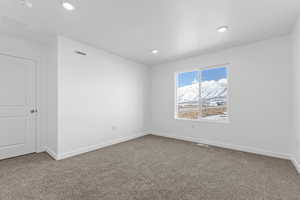 Carpeted spare room with visible vents, baseboards, and recessed lighting