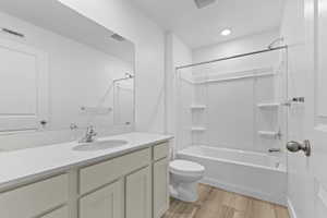Bathroom with shower / washtub combination, vanity, visible vents, toilet, and wood finished floors