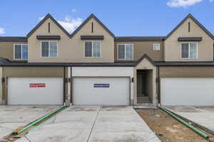 Multi unit property with a garage, stucco siding, and concrete driveway