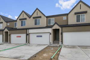 Multi unit property with a garage, stucco siding, and concrete driveway