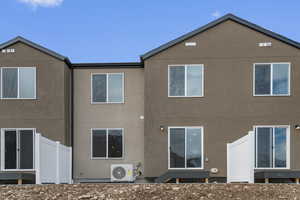 Rear view of property featuring stucco siding, fence, and ac unit