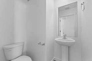 Half bath featuring visible vents, baseboards, a sink, and toilet