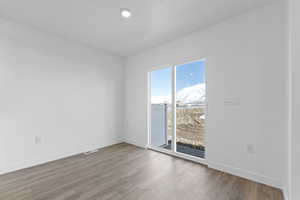 Empty room featuring visible vents, baseboards, and wood finished floors