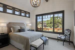 Carpeted bedroom featuring baseboards and a chandelier