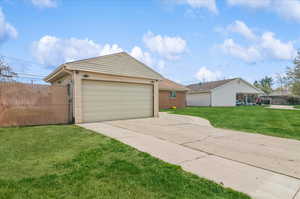View of front facade with an outdoor structure, concrete driveway, a front lawn, and brick siding