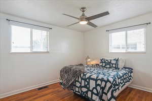 Bedroom with wood finished floors, baseboards, and multiple windows