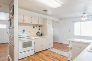 Kitchen featuring tasteful backsplash, light wood-type flooring, white range with electric stovetop, and plenty of natural light