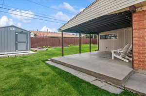 View of yard with a patio, an outbuilding, a storage unit, and fence