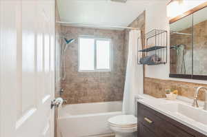 Full bath with visible vents, toilet, vanity, and shower / bath combination with curtain