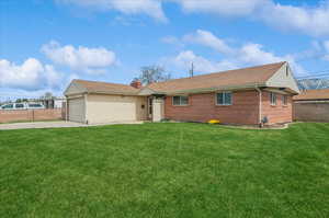 Ranch-style home featuring an attached garage, a chimney, concrete driveway, and a front lawn