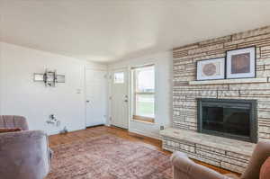 Living area with wood finished floors, a fireplace, baseboards, and visible vents
