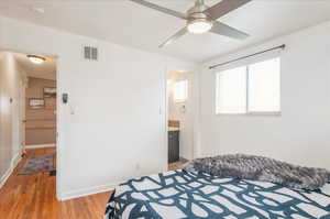 Bedroom with visible vents, baseboards, connected bathroom, and light wood-style flooring