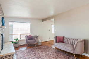 Sitting room featuring a stone fireplace, baseboards, and wood finished floors