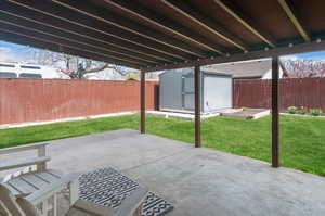 View of patio / terrace with a storage shed, a fenced backyard, a vegetable garden, and an outdoor structure