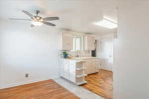Bathroom with vanity, baseboards, ceiling fan, decorative backsplash, and wood finished floors