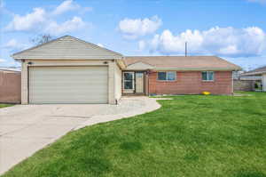 Single story home featuring a garage, fence, concrete driveway, brick siding, and a front lawn