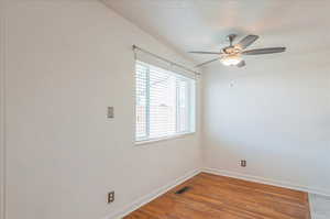 Unfurnished room featuring visible vents, baseboards, ceiling fan, and wood finished floors