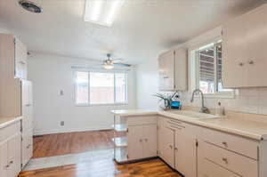 Kitchen featuring ceiling fan, light wood-type flooring, visible vents, a sink, and backsplash