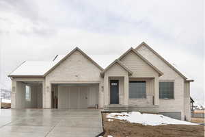 View of front of property featuring brick siding, an attached garage, and driveway