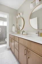 Full bath with tile patterned floors, double vanity, a sink, and a stall shower
