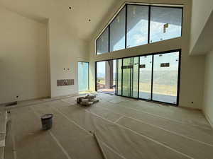 Unfurnished living room with high vaulted ceiling