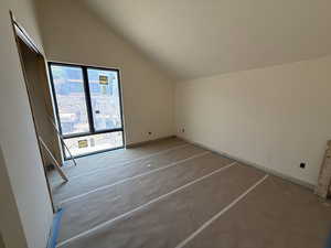 Bedroom with vaulted ceiling and concrete floors
