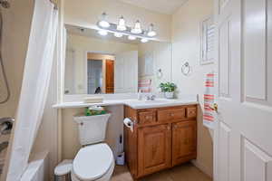 Bathroom with vanity, visible vents, toilet, tile patterned floors, and shower / bath combo with shower curtain
