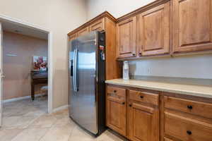 Kitchen featuring brown cabinetry, light countertops, stainless steel fridge, and visible vents