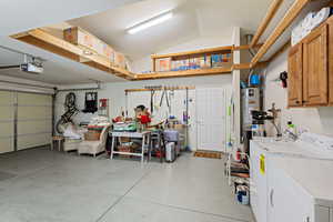 Garage featuring washer and dryer, a garage door opener, and strapped water heater