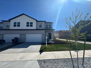View of front of home with a garage, driveway, board and batten siding, and a front lawn