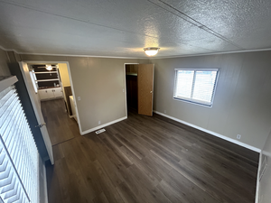Unfurnished bedroom with crown molding, visible vents, baseboards, and dark wood-type flooring