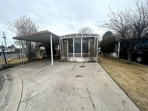 Back of house featuring a yard, concrete driveway, and an attached carport