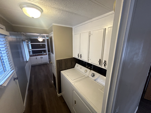 Laundry area with ceiling fan, dark wood finished floors, a textured ceiling, washing machine and dryer, and cabinet space