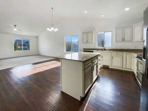 Kitchen featuring open floor plan, dark stone countertops, cream cabinets, and a sink