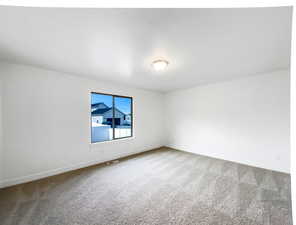 Carpeted empty room with visible vents and baseboards