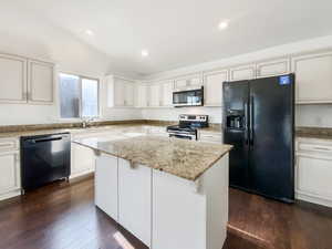 Kitchen with dark wood-type flooring, appliances with stainless steel finishes, a sink, and vaulted ceiling