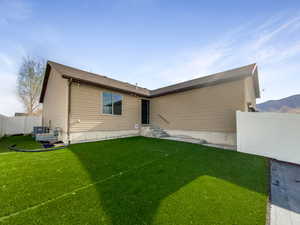 Rear view of house featuring a yard and fence