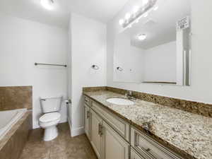 Full bath with vanity, tile patterned flooring, visible vents, toilet, and a relaxing tiled tub
