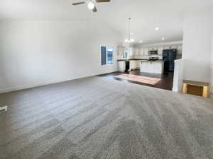 Unfurnished living room featuring baseboards, recessed lighting, a ceiling fan, dark carpet, and high vaulted ceiling