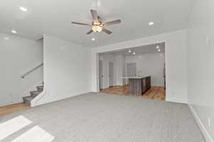 Unfurnished living room with light carpet, recessed lighting, stairway, and a ceiling fan