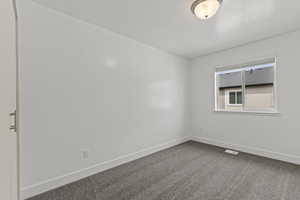 Unfurnished room featuring dark colored carpet, visible vents, and baseboards