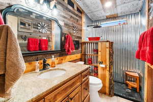 Full bath featuring wood walls, vanity, walk in shower, and toilet
